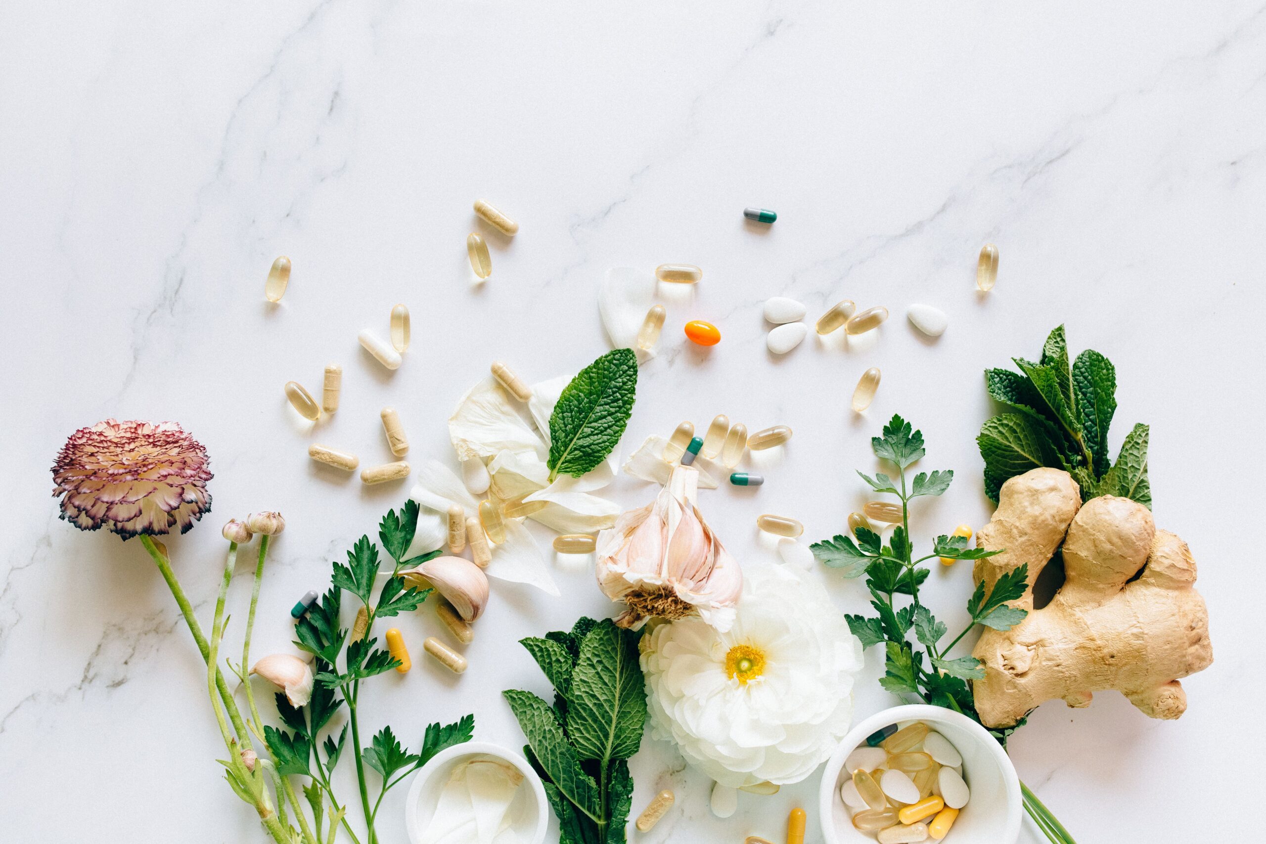 Natural herbs and pills arranged on a marble surface for a holistic healthcare theme.